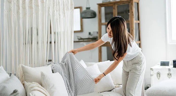 Women fixing thro pillows in sofa